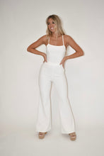 Load image into Gallery viewer, women&#39;s clothing boutique, model is wearing a white denim jumpsuit that is sleeveless and has an open back 
