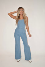 Load image into Gallery viewer, women&#39;s clothing boutique, online women&#39;s clothing boutique, model modeling light wash denim jumpsuit, open back jumpsuit, flare denim jumpsuit, denim overalls
