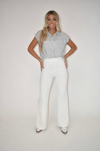 Load image into Gallery viewer, Model is modeling our white denim jumpsuit with a stripe tank top over it perfect for spring and summer wear
